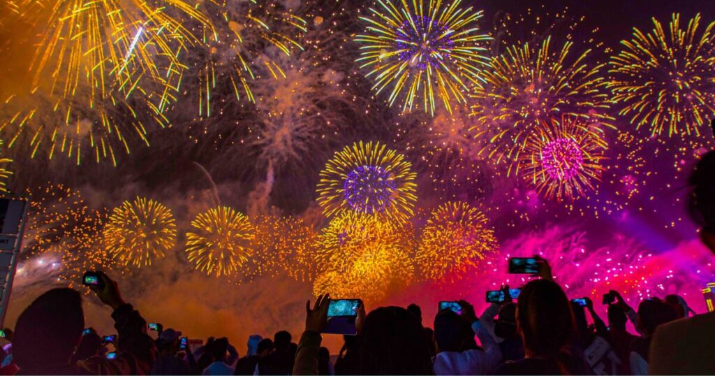 夜空に連打された花火をスマホで思い出に残そうとしている人たち